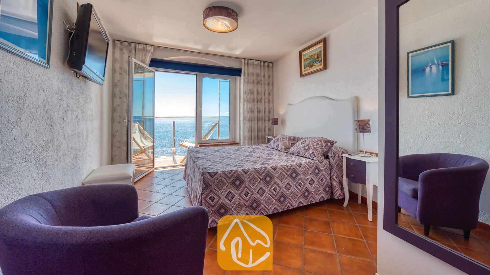 Vakantievilla's Costa Brava Spanje - Villa Infinity - Slaapkamer in Villa Infinity met een tweepersoonsbed, een gedessineerde paarse sprei en openslaande glazen deuren die leiden naar een balkon met uitzicht op zee