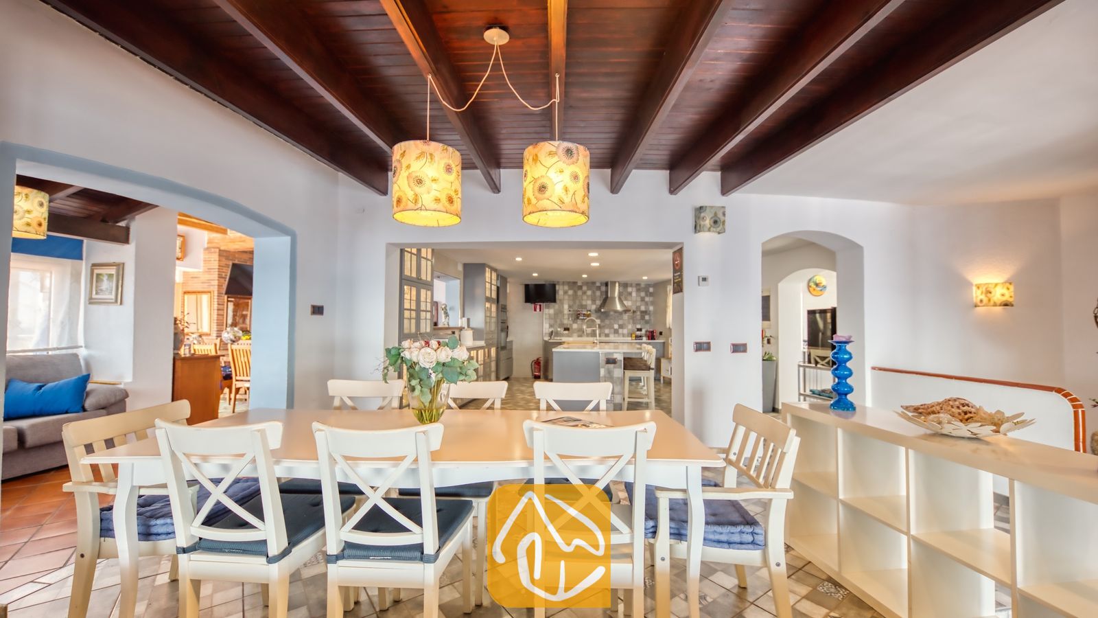 Vakantievilla's Costa Brava Spanje - Villa Infinity - Eetgedeelte met een wit houten tafel omringd door stoelen met blauwe kussens, gesitueerd onder een plafond met donkere houten balken bij Villa Infinity.