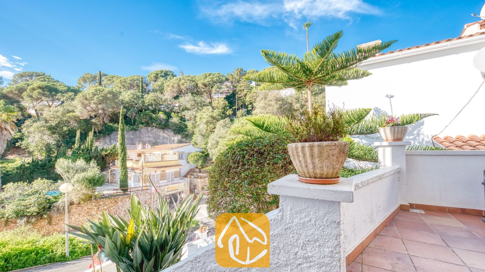 Vakantievilla's Costa Brava Spanje - Villa Blanca - Uitzicht vanaf het balkon van Villa Blanca op de groene heuvels en terracotta dakpannen onder een blauwe hemel.
