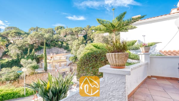 Vakantievilla's Costa Brava Spanje - Villa Blanca - Uitzicht vanaf het balkon van Villa Blanca op de groene heuvels en terracotta dakpannen onder een blauwe hemel.