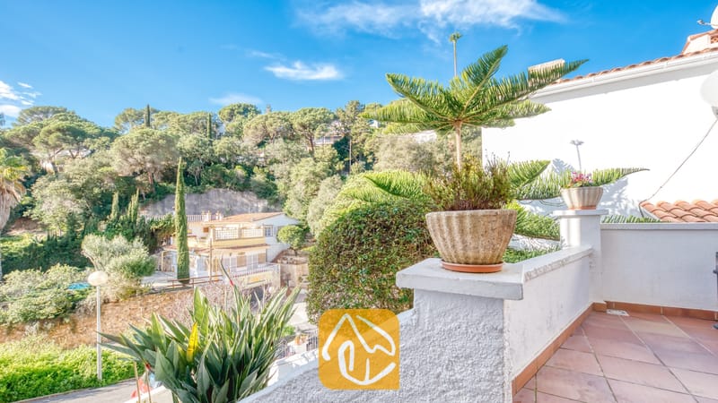 Vakantievilla's Costa Brava Spanje - Villa Blanca - Uitzicht vanaf het balkon van Villa Blanca op de groene heuvels en terracotta dakpannen onder een blauwe hemel.