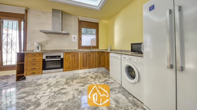 Vakantievilla's Costa Brava Spanje - Villa Baileys - Keuken van Villa Baileys met houten kasten, marmeren aanrechtbladen, roestvrijstalen apparatuur en een wasmachine.