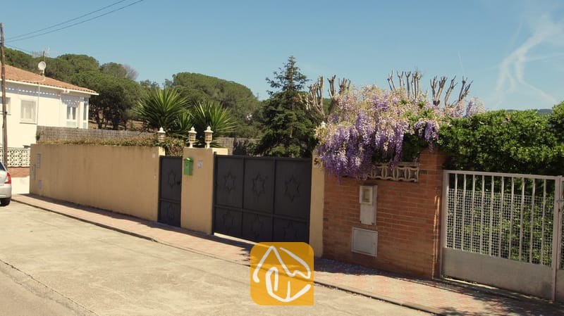 Villas de vacances Costa Brava Espagne - Villa Miro - Des portails en métal noir ornés de motifs étoilés marquent l'entrée de la Villa Miro, qui se distingue par son mur d'enceinte jaune et ses glycines violettes retombant sur des briques rouges.