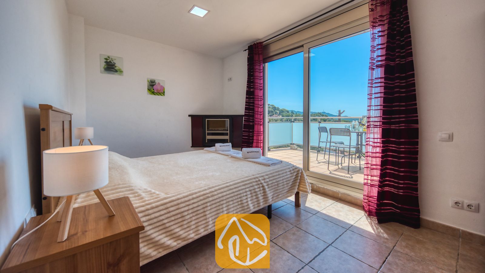 Vakantievilla's Costa Brava Spanje - Villa Sandy Beach - Slaapkamer in Villa Sandy Beach met een tweepersoonsbed, tegelvloeren en grote glazen schuifdeuren die uitkomen op een terras met zitgelegenheid buiten en uitzicht op de groene heuvels.