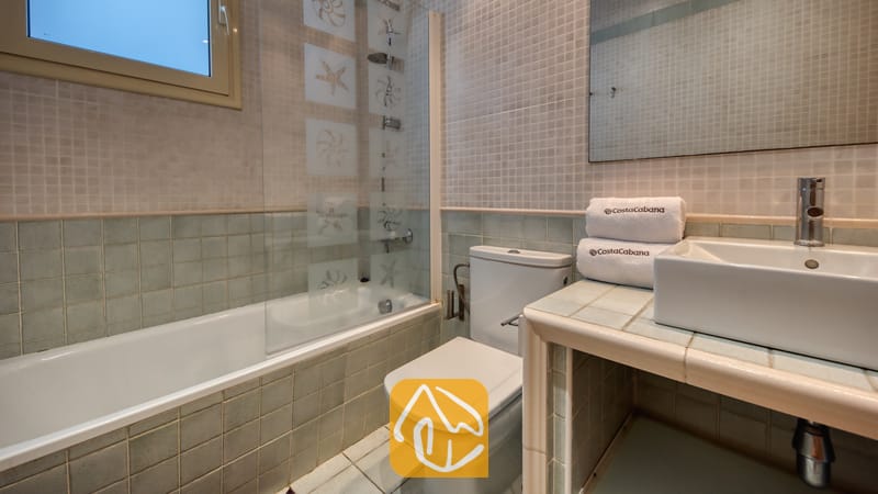 Villas de vacances Costa Brava Espagne - Villa Sandy Beach - Salle de bain équipée d'une baignoire avec paroi vitrée ornée de motifs d'étoiles de mer, mosaïque vert clair et vasque blanche posée sur un meuble sous-vasque carrelé.