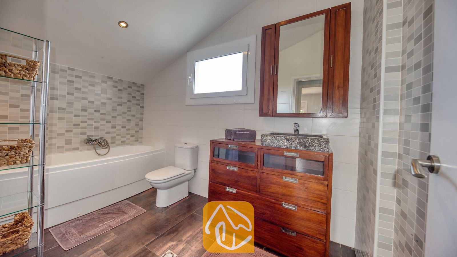 Vakantievilla's Costa Brava Spanje - Villa Madonna - Moderne badkamer met een houten wastafelmeubel, een stenen waskom, een wit ligbad en grijze mozaïektegelaccenten.