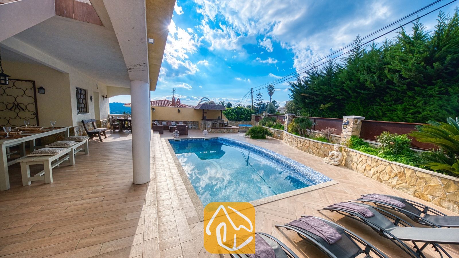 Vakantievilla's Costa Brava Spanje - Villa Madonna - Privézwembad en betegeld terras bij Villa Madonna, voorzien van vier ligbedden en een overdekte eethoek buiten onder een helderblauwe hemel.