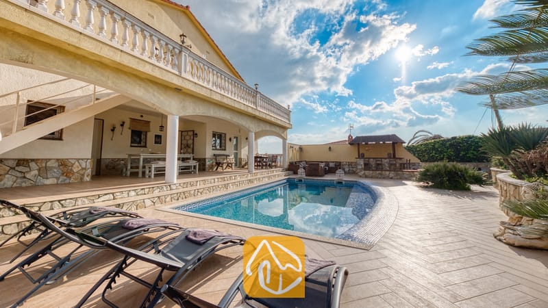 Vakantievilla's Costa Brava Spanje - Villa Madonna - Privézwembad met ligstoelen op het betegelde terras van Villa Madonna in Spanje, voorzien van een overdekt terras en stenen muren onder een zonnige hemel