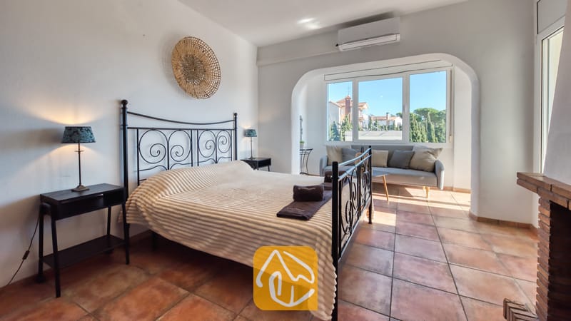 Villas de vacances Costa Brava Espagne - Villa Madonna - Chambre à coucher avec un lit en fer forgé noir, un plaid texturé blanc et un sol en carrelage en terre cuite.