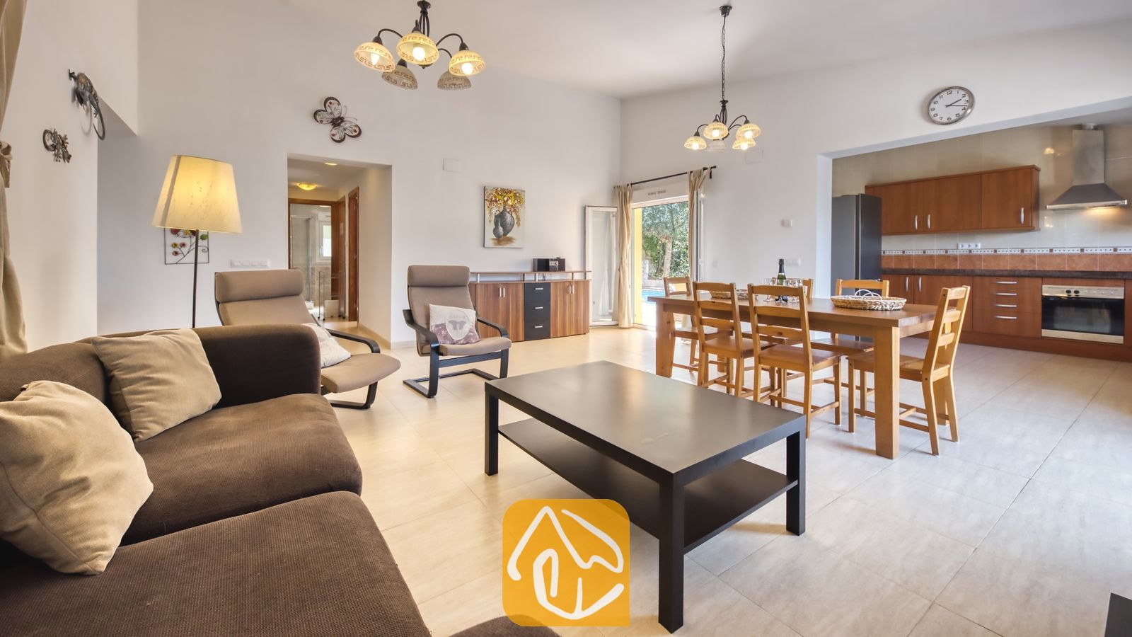 Vakantievilla's Costa Brava Spanje - Villa Esmee - Open en licht woon- en eetgedeelte in Villa Esmee, voorzien van een bruine bank, een zwarte salontafel, een houten eethoek en een aangrenzende keuken.