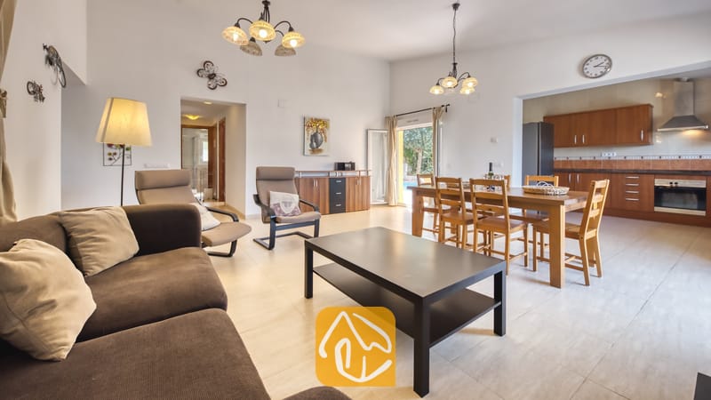 Vakantievilla's Costa Brava Spanje - Villa Esmee - Open en licht woon- en eetgedeelte in Villa Esmee, voorzien van een bruine bank, een zwarte salontafel, een houten eethoek en een aangrenzende keuken.