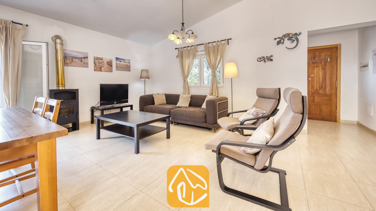 Vakantievilla's Costa Brava Spanje - Villa Esmee - Interieur van de woonkamer in Villa Esmee met een bruine bank, zwarte salontafel, twee fauteuils en een houtkachel.