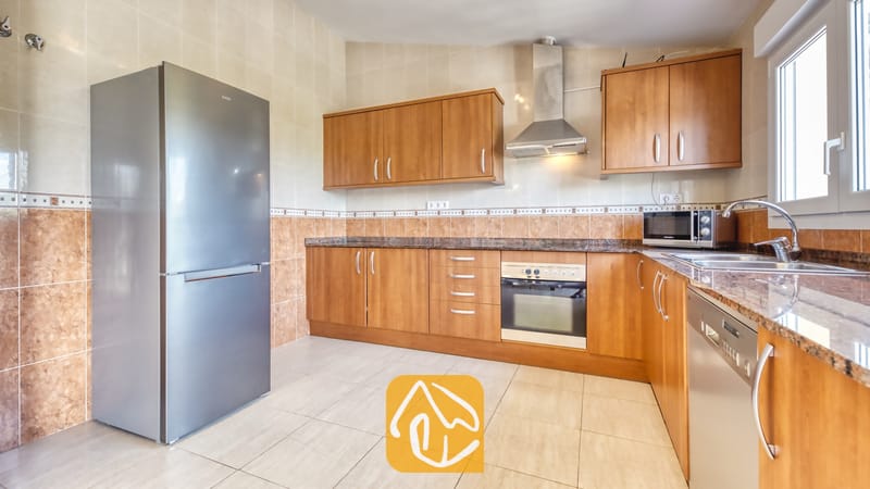 Vakantievilla's Costa Brava Spanje - Villa Esmee - Keuken voorzien van houten kasten, granieten aanrechtbladen en een roestvrijstalen koelkast.