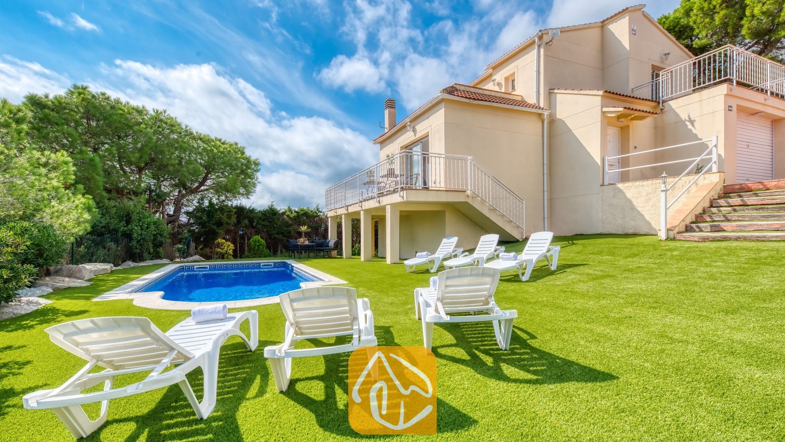 Vakantievilla's Costa Brava Spanje - Villa La Luna - Privézwembad en witte ligstoelen op een groen gazon bij de buitenkant van Villa La Luna in Spanje.
