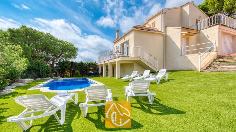 Vakantievilla's Costa Brava Spanje - Villa La Luna - Privézwembad en witte ligstoelen op een groen gazon bij de buitenkant van Villa La Luna in Spanje.