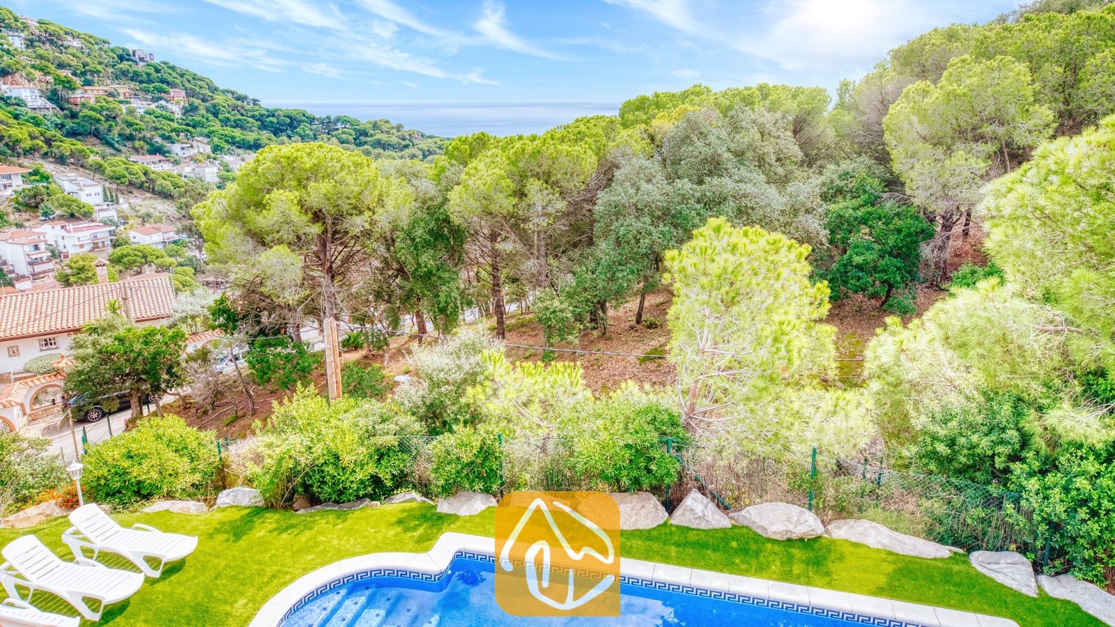 Vakantievilla's Costa Brava Spanje - Villa La Luna - Privézwembad met helderblauw water en witte ligbedden bij Villa La Luna, met uitzicht op groene bossen, heuvels en de zee onder een stralend blauwe lucht.