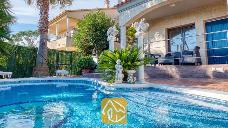 Vakantievilla's Costa Brava Spanje - Villa Grace - Buitenzwembad met betegelde treden bij Villa Grace, voorzien van decoratieve zuilen, standbeelden en een palmboom in de tuin.