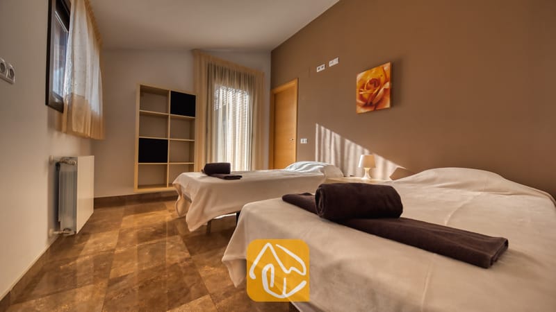 Villas de vacances Costa Brava Espagne - Villa Grace - Chambre à deux lits simples habillés de linge blanc et de serviettes marron, sols carrelés, murs marrons et peinture murale florale.