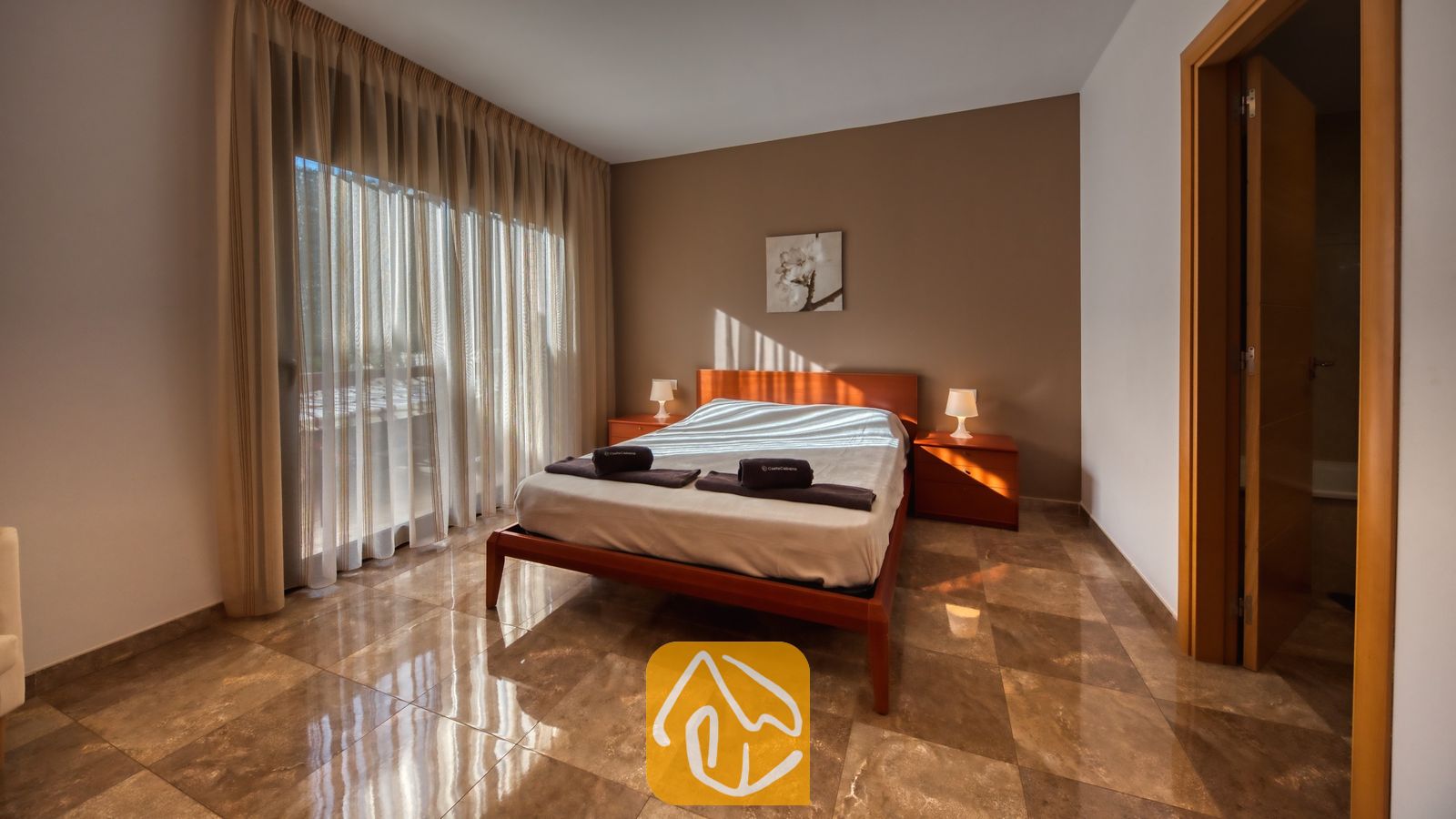 Vakantievilla's Costa Brava Spanje - Villa Grace - Slaapkamer met een houten bedframe, transparante kamerhoge gordijnen en betegelde vloeren bij Villa Grace