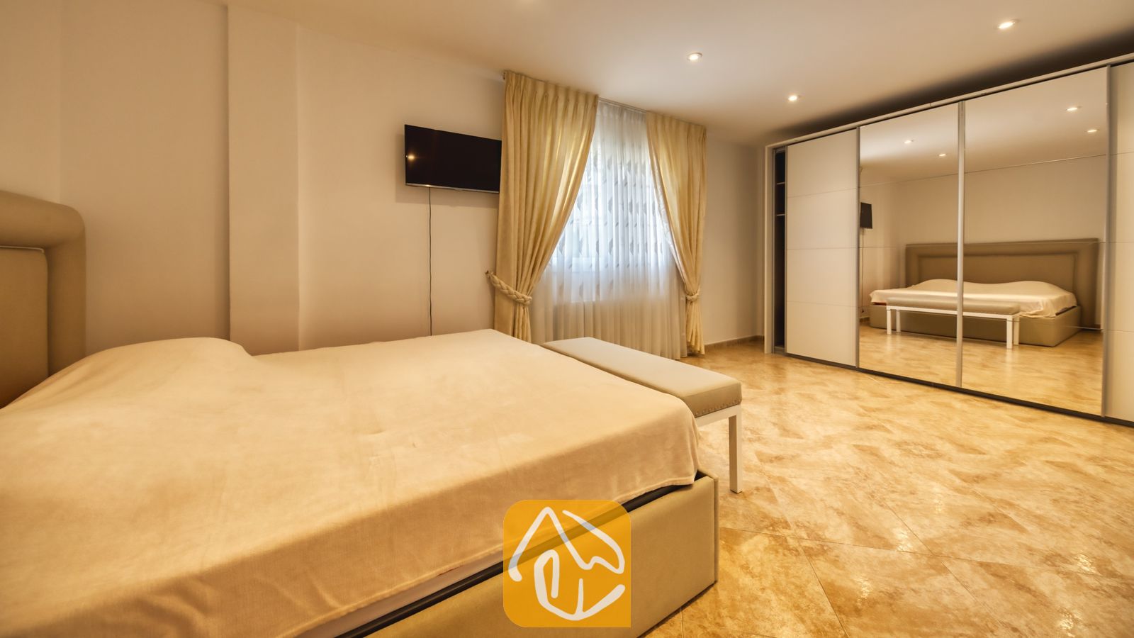 Vakantievilla's Costa Brava Spanje - Villa Lorena - Slaapkamer in Villa Lorena, voorzien van een groot bed met neutraal beddengoed, een wall-mounted flatscreen-tv en een grote spiegelkledingkast.