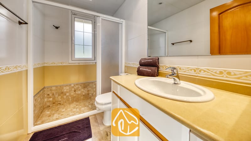 Villas de vacances Costa Brava Espagne - Villa Lorena - Salle de bain dotée d'un meuble-lavabo blanc, d'une douche à l'italienne et de serviettes marron pliées disposées sur le comptoir.