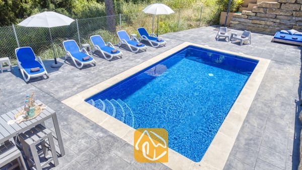 Vakantievilla's Costa Brava Spanje - Villa Fransisca - Privé-buitenzwembad bij Villa Fransisca met helderblauw water en betegelde treden, omringd door meerdere witte ligstoelen en twee witte parasols op een grijs betegeld terras.