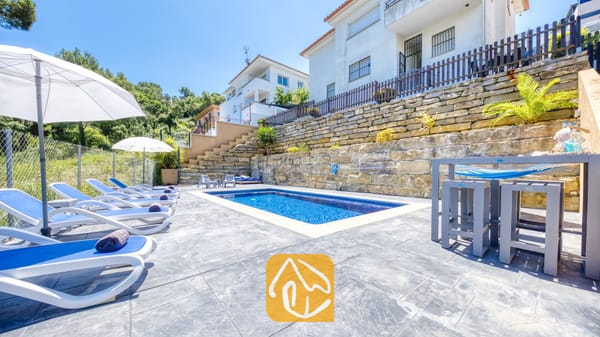 Vakantievilla's Costa Brava Spanje - Villa Fransisca - Privézwembad bij Villa Fransisca, voorzien van blauwe ligstoelen, witte parasols en een stenen keermuur onder een helderblauwe hemel