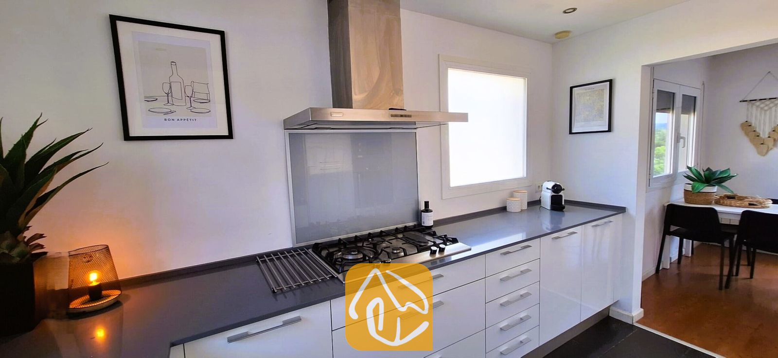 Vakantievilla's Costa Brava Spanje - Villa Fransisca - Moderne keuken met witte kasten, donkergrijze aanrechtbladen, een roestvrijstalen gaskookplaat en afzuigkap in Villa Fransisca.