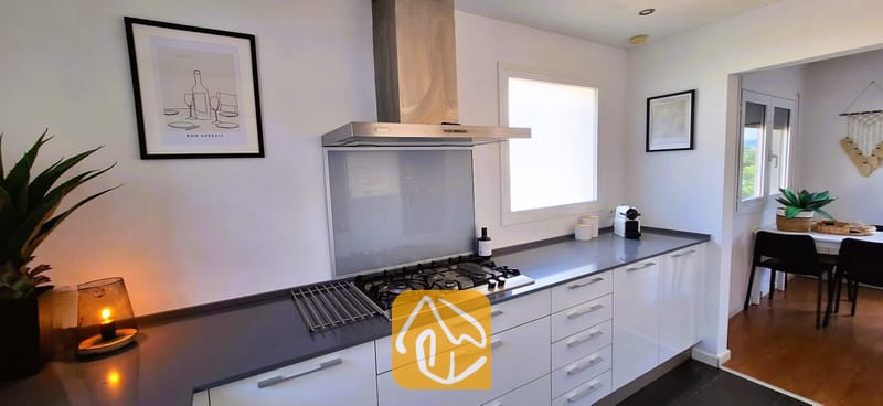 Villas de vacances Costa Brava Espagne - Villa Fransisca - Cuisine moderne dotée de placards blancs, de plans de travail gris foncé, ainsi que d'une table de cuisson à gaz en acier inoxydable et d'une hotte aspirante à la Villa Fransisca.