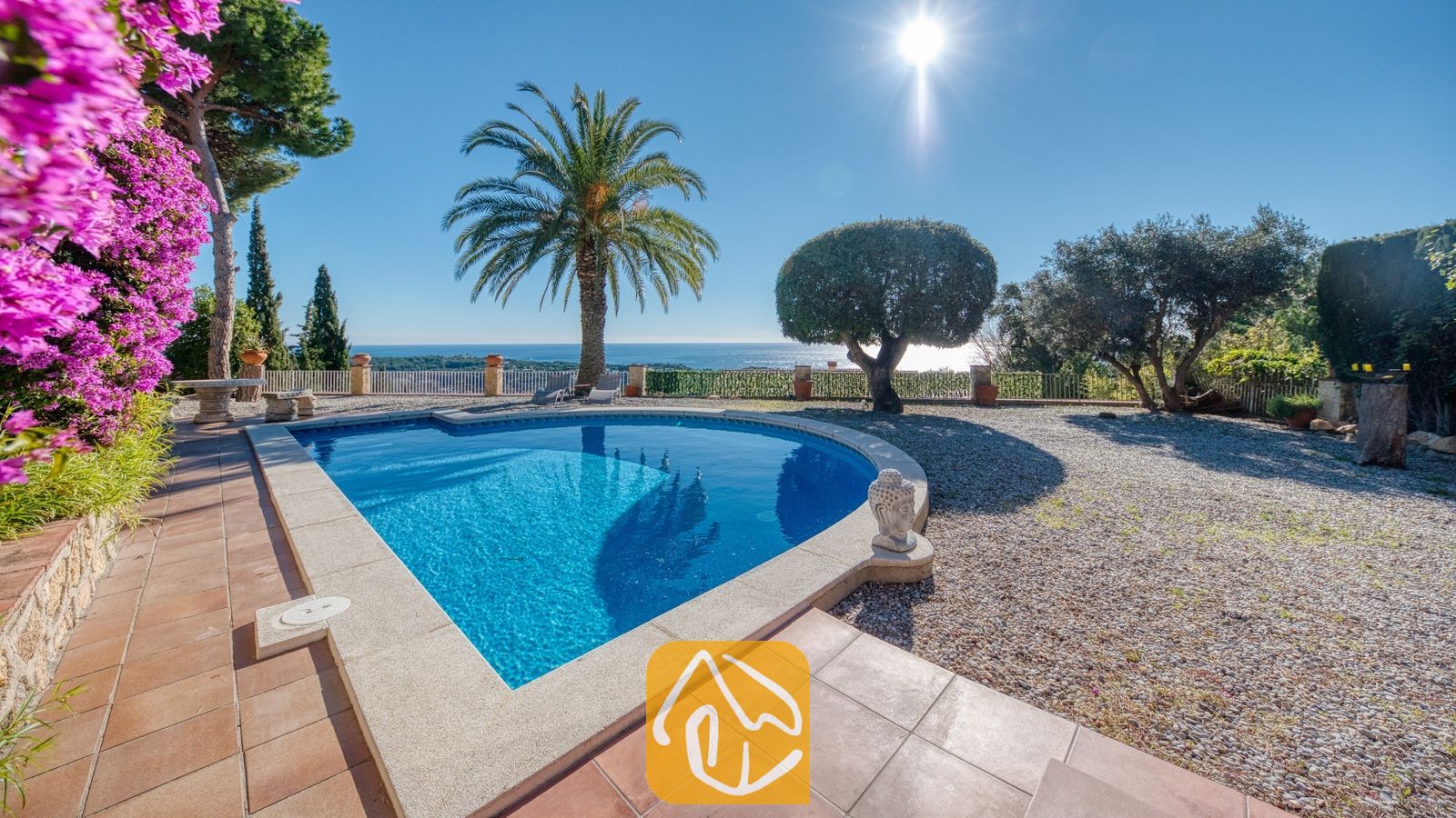 Vakantievilla's Costa Brava Spanje - Villa Gabriella - Privézwembad bij Villa Gabriella met uitzicht op zee, een palmboom en een stenen Boeddhabeeld op het betegelde terras.