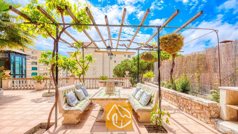Vakantievilla's Costa Brava Spanje - Villa Dolce Vita - Buiten eettafel van steen onder een houten pergola met klimplanten op het dakterras van Villa Dolce Vita.