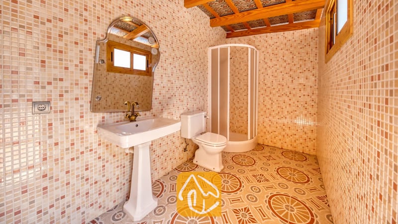 Vakantievilla's Costa Brava Spanje - Villa Dolce Vita - Badkamer met een vrijstaande wastafel, een gebogen glazen douchecabine en gedecoreerde vloertegels, dit alles omringd door beige mozaïekwanden.