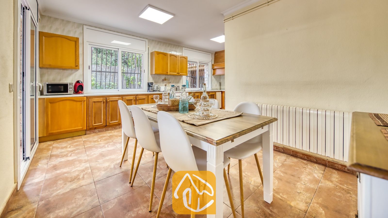 Vakantievilla's Costa Brava Spanje - Villa Dolce Vita - Keuken en eethoek voorzien van een houten eettafel met witte stoelen, houten kasten en een tegelvloer.