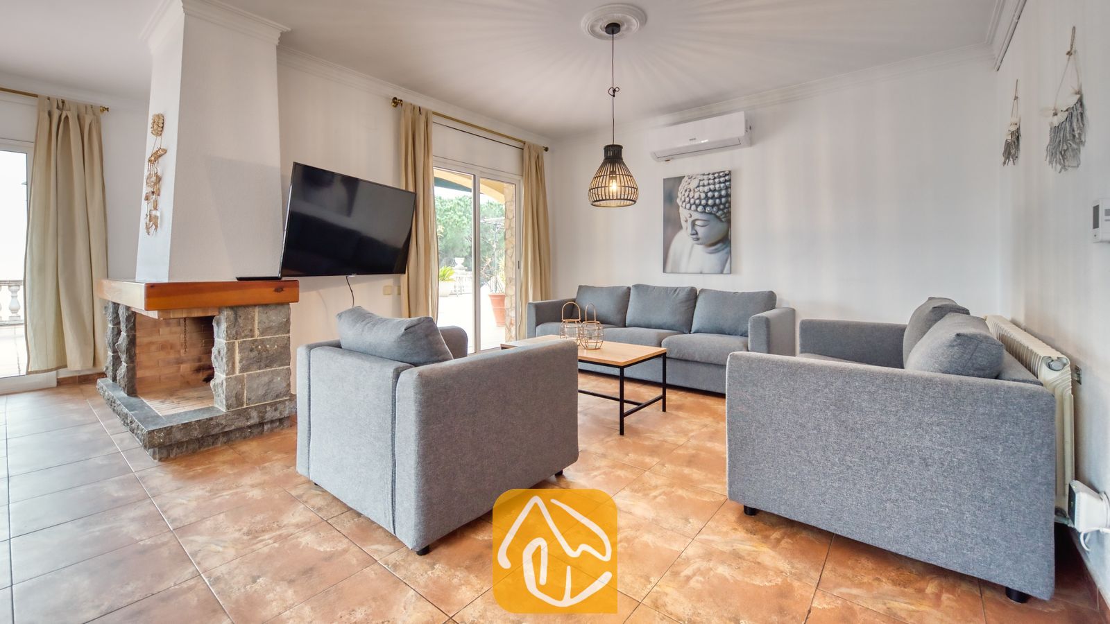 Vakantievilla's Costa Brava Spanje - Villa Dolce Vita - Woonkamer met grijs gestoffeerde banken, een stenen open haard en tegelvloeren in Villa Dolce Vita