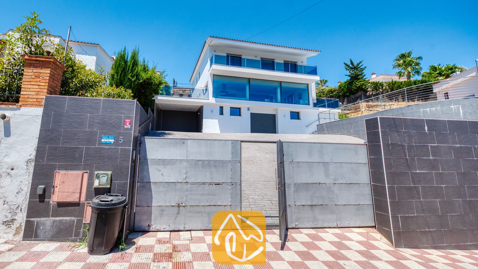 Vakantievilla's Costa Brava Spanje - Villa SummerDream - Buitenkant van Villa SummerDream met een witte, meerdere verdiepingen tellende gevel, grote glazen ramen en een stalen veiligheidshek tegen een helderblauwe hemel