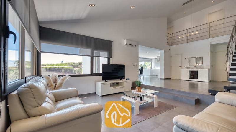 Vakantievilla's Costa Brava Spanje - Villa SummerDream - Ruime open woonkamer in Villa SummerDream met lichte leren banken, een glazen salontafel en grote ramen met rolgordijnen.