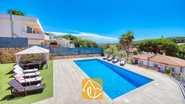 Vakantievilla's Costa Brava Spanje - Villa SummerDream - Privézwembad en terras bij Villa SummerDream in Spanje, voorzien van ligstoelen, een schaduwrijke gazebo en omringende groene bomen onder een helderblauwe hemel.