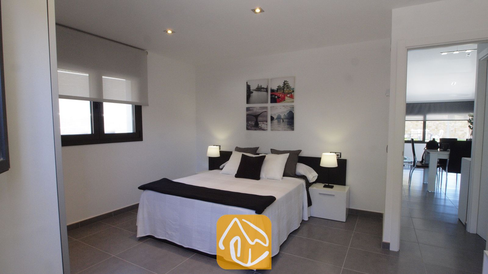 Vakantievilla's Costa Brava Spanje - Villa SummerDream - Slaapkamer met een tweepersoonsbed voorzien van wit en zwart beddengoed, twee nachtkastlampjes en vier kleine wanddecoraties.