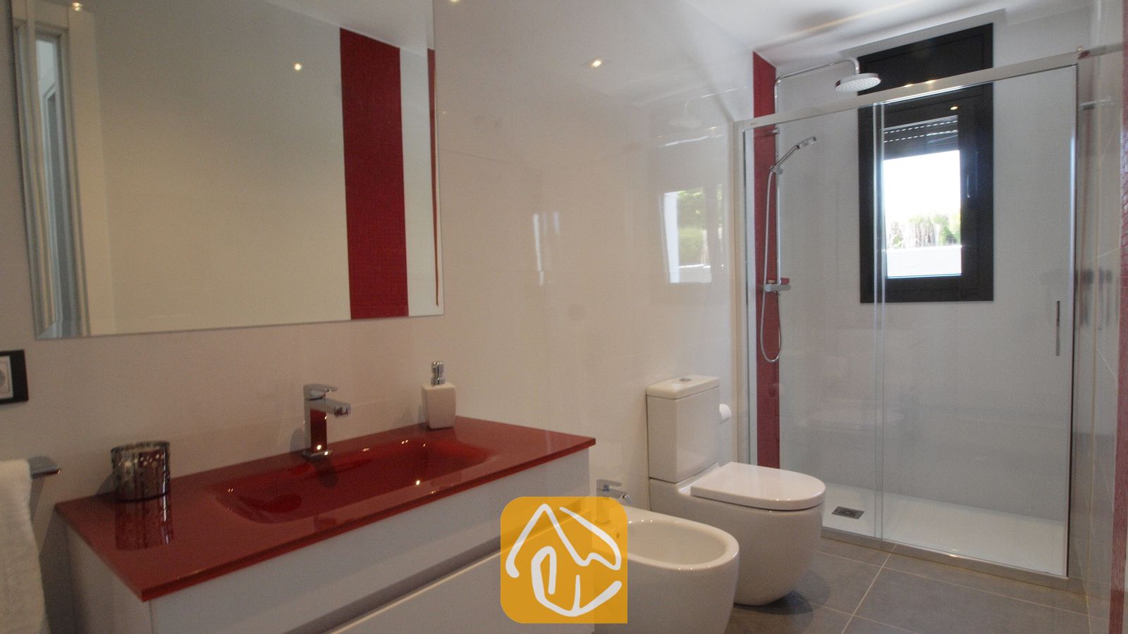 Vakantievilla's Costa Brava Spanje - Villa SummerDream - Moderne badkamer met een rode waskom op een wit badmeubel, een glazen inloopdouche en een bijpassend wit toilet en bidet tegen wit-met-rode muren.