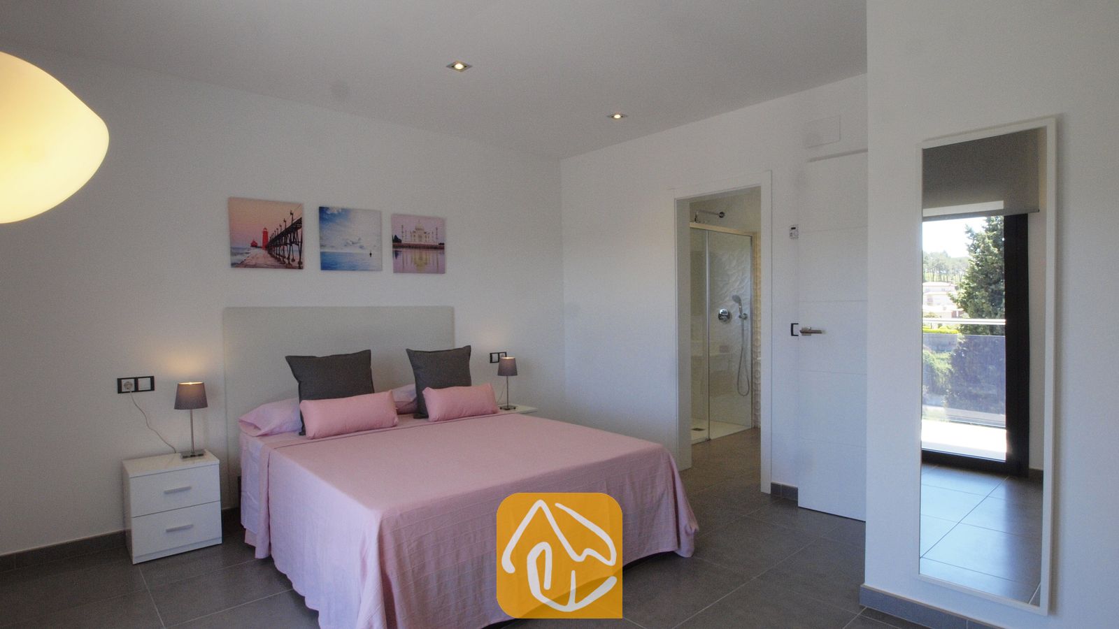 Vakantievilla's Costa Brava Spanje - Villa SummerDream - Slaapkamer met roze beddengoed, twee nachtkastjes met lampen en een deur naar de en-suite badkamer die zichtbaar is.