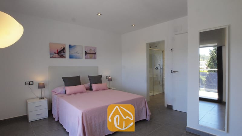 Villas de vacances Costa Brava Espagne - Villa SummerDream - Chambre avec parure de lit rose, deux tables de chevet avec lampes, et porte de salle de bains attenante visible.