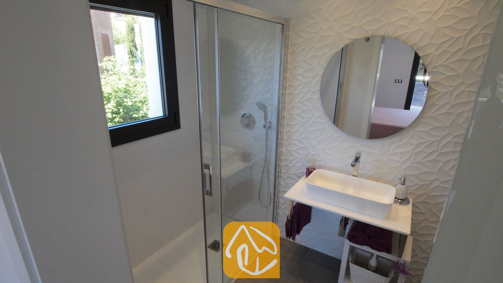 Vakantievilla's Costa Brava Spanje - Villa SummerDream - Moderne badkamer met een glazen inloopdouche, een witte waskom op een badkamermeubel, een ronde spiegel en gestructureerde witte wandtegels.