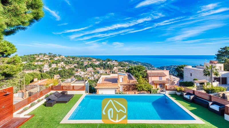 Vakantievilla's Costa Brava Spanje - Villa Chanel - Privézwembad bij Villa Chanel met kunstgras, zwarte loungeset en een panoramisch uitzicht over de Middellandse Zee en het kustplaatsje.