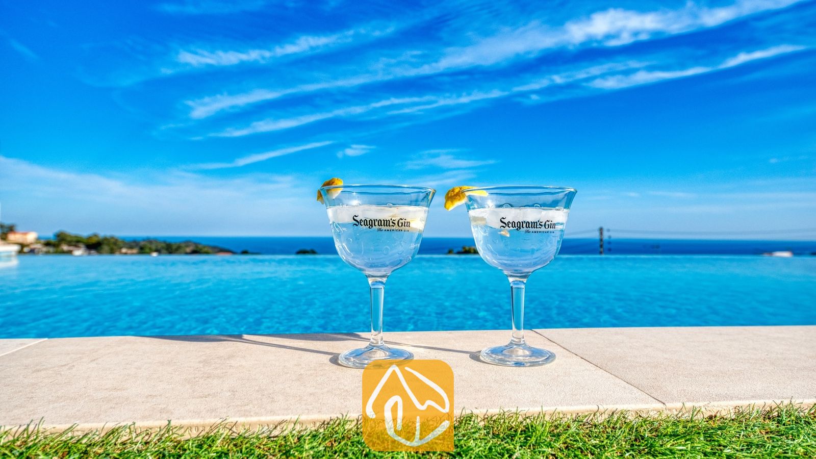 Vakantievilla's Costa Brava Spanje - Villa Chanel - Twee gin-cocktails met citroengarnituur aan de rand van het overloopzwembad van Villa Chanel, met uitzicht op de blauwe zee en de lucht.
