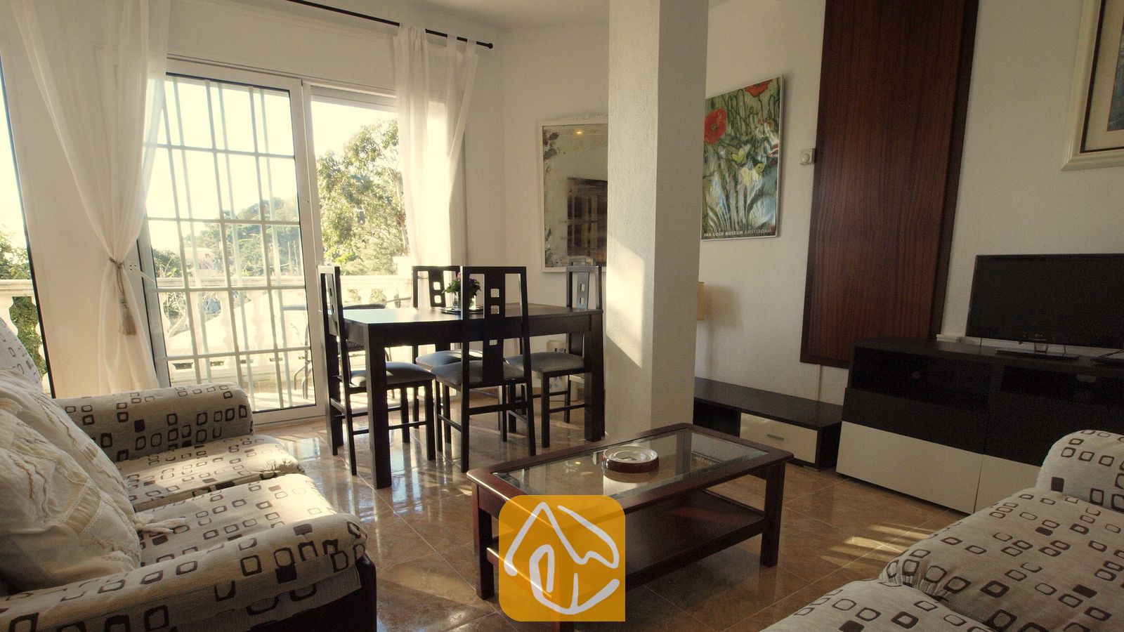 Vakantievilla's Costa Brava Spanje - Villa Noa - Woonkamer met beklede banken met patroon, een salontafel met glazen blad en een eethoek nabij de balkondeur in Villa Noa.