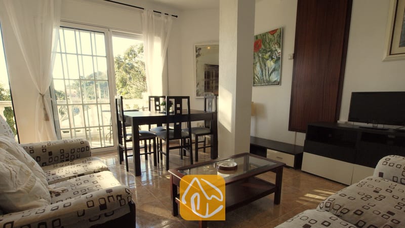 Vakantievilla's Costa Brava Spanje - Villa Noa - Woonkamer met beklede banken met patroon, een salontafel met glazen blad en een eethoek nabij de balkondeur in Villa Noa.