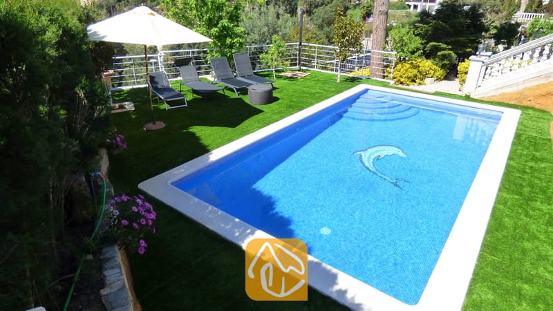 Vakantievilla's Costa Brava Spanje - Villa Noa - Privézwembad met een dolfijnmozaiëk bij Villa Noa, omringd door kunstgras, ligstoelen en een parasol.