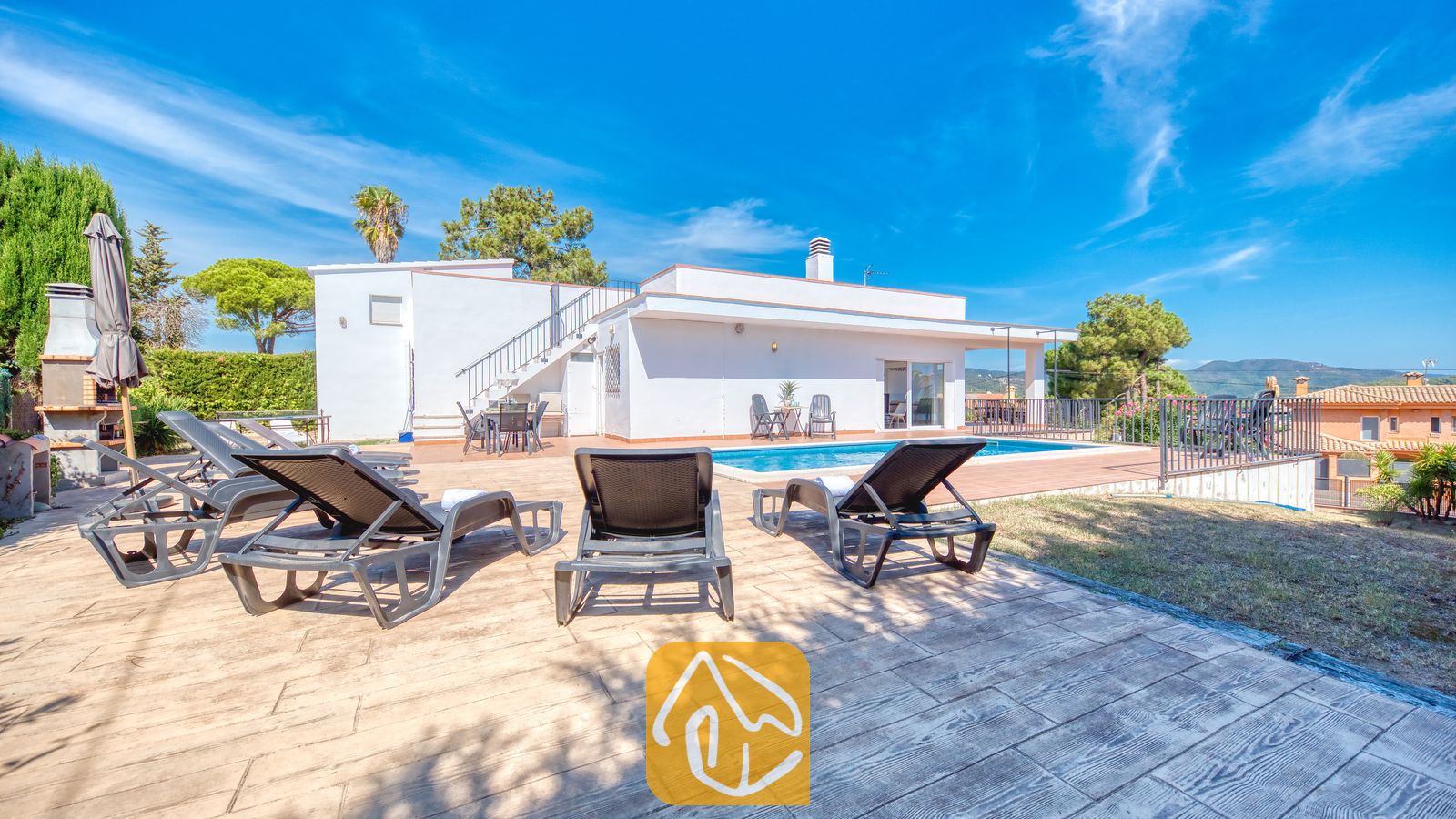 Holiday villas Costa Brava Spain - Villa Yara - Private outdoor swimming pool at Villa Yara surrounded by dark loungers on a paved terrace under a bright blue sky.