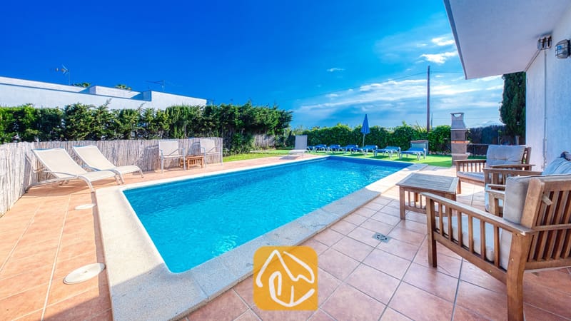 Vakantievilla's Costa Brava Spanje - Villa Yara - Privé buitenzwembad bij Villa Yara met betegeld terras, houten fauteuils en ligstoelen tegen een blauwe hemel.