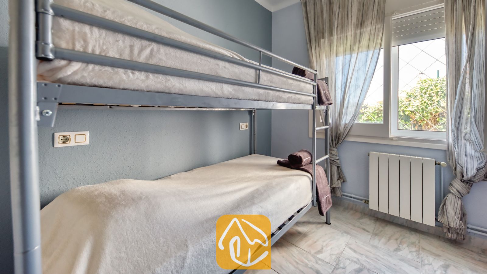 Vakantievilla's Costa Brava Spanje - Villa Yara - Slaapkamer met grijs metalen stapelbed, wit beddengoed en een raam met inbetween-gordijnen in Villa Yara